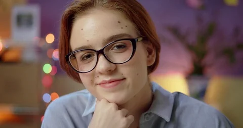 Close up of cute Caucasian nerd ginger girl pleasantly looking to camera cozy Stock Footage 125315070