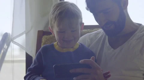 Close on cute dad and son playing with cell phone Stock Footage 64384915