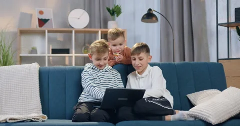 Close up of cute happy smiling three boys which sitting on the comfortable couch 스톡 동영상 151911627