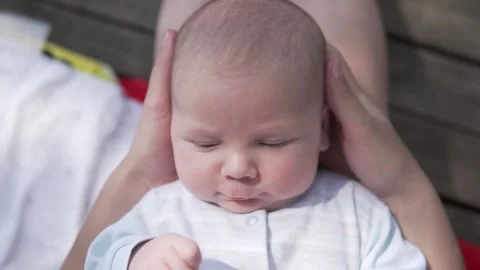 Close-up of cute infant baby Boy in mom's arms Stock Footage 135304418