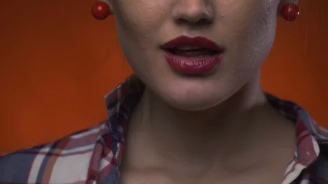 Close up of a cute lady with red lipstick biting on a colorful lollipop Stock Footage 103302736