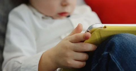 Close up of the cute little blonde boy sitting on the couch with the tablet Stock Footage 82916005