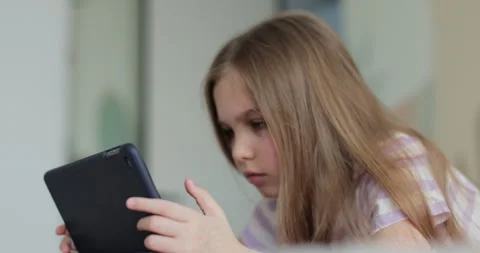 Close-up of a cute little girl using a digital tablet at home Stock Footage 335644016
