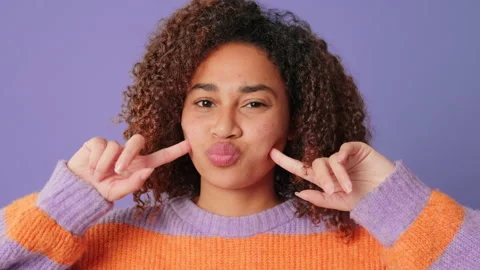 Close-up of cute smiling woman making funny faces looking at camera on lilac Stock Footage 283563687
