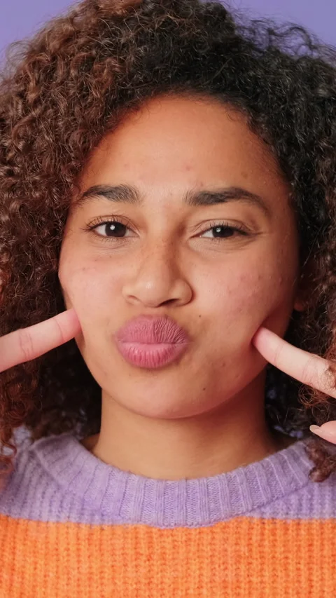 Close-up of cute smiling woman making funny faces looking at camera on lilac Stock Footage 287874468