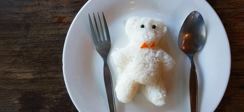 Close up cute teddy bear shape made from white rice with spoon and fork Stock Photos