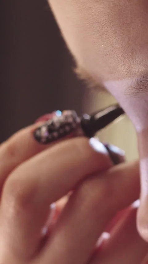Close-up of cute young girl doing makeup - drawing dramatic winged eyeliner Stock Footage 328075429