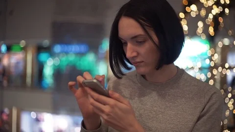 Close up of cute young girl using smartphone chatting online in shopping mall Stock Footage 83368734