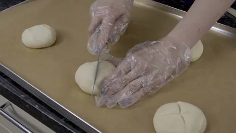 Close up of cuts are being made on the bun by female baker. Video stock 85710635