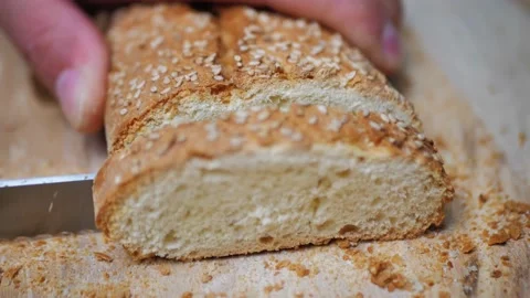 Close-up of cutting bread with sesame seeds. A man's hand holds a burger bun for Stock Footage 215994121