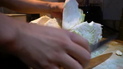 Close up cutting cabbage with a knife on a kitchen board with hands Видео 146020669