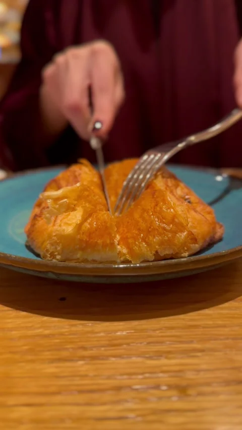Close-up of cutting a crispy chocolate croissant with knife and fork on a plate Vídeo Stock 337462137