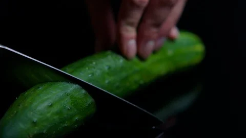 Close up of cutting cucumber with knife. Black mirror surface Stock Footage 92550056