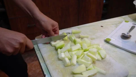 Close up cutting cucumber into pieces with a knife in hand in the kitchen Stock Footage 145998003