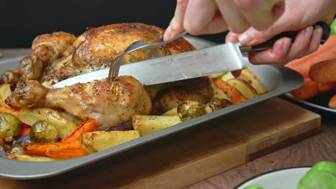 Close-up of cutting with a fork and knife a whole organic roasted chicken. Stock Footage 145117791