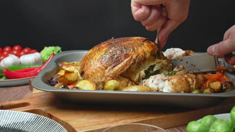 Close-up of cutting with a fork and knife a whole organic roasted chicken. Stock Footage 145118026