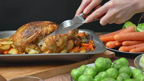 Close-up of cutting with a fork and knife a whole organic roasted chicken. Stock Footage 145118126