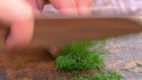 Close-up of cutting green dill on a board in the kitchen on a wooden board 库存影片 248898344