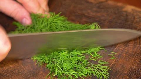 Close-up of cutting green dill on a board in the kitchen on a wooden board Stockbeeldmateriaal 250442082