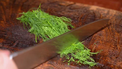 Close-up of cutting green dill on a board in the kitchen on a wooden board Stock Footage 254687972