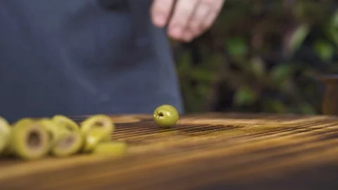 Close up cutting green olives with knife on wooden table. Hands of chef cook Video stock 98480053