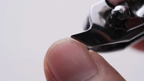 Close-up of cutting nails using nail clipper on white background - Video 4K Stock Footage 128334814