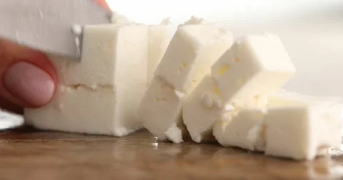 Close-up of Cutting or slicing cubes of feta cheese on a board. Stock Footage 250482407