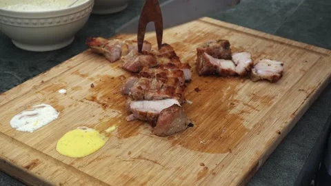 Close-up cutting into pieces a grilled meat with a knife on a wooden board at Stock Footage 178465560