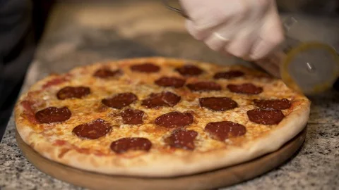 Close up of cutting ready hot pizza into four pieces on cooking table Stock Footage 105294712