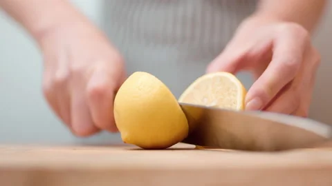 Close-up cutting, slicing a lemon in half with a chef knife by a woman in 4K. Stock Footage 138285375