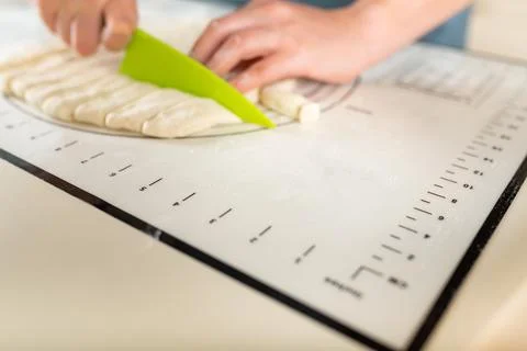 Close-up on cutting wheat dough on a kitchen mat with markings with a plastic Stock Photos