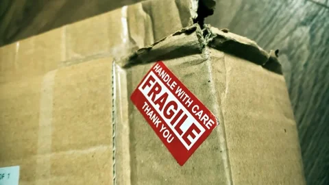 Close-up of damaged cardboard parcel with red fragile handle with care sticker Stock Footage 336873485