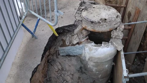 Close-up of a damaged concrete manhole surrounded by construction barriers and e Stock Footage 304885396