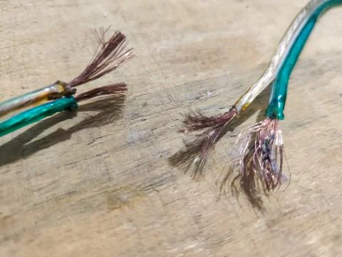 Close up of damaged electrical wire with exposed copper strands on wooden surfac Stockfoto's