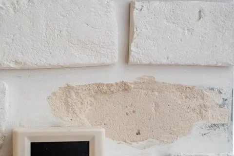 Close up of a damaged white decorative brick wall with a missing tile leaving a Stock Photos