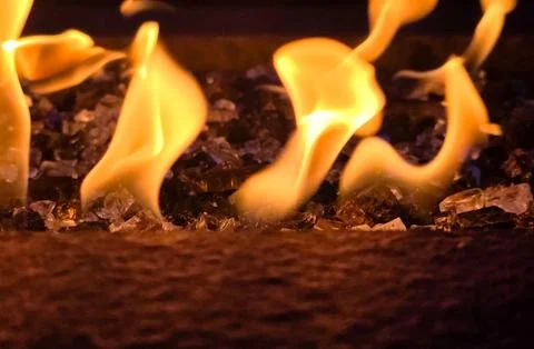 Close-Up of Dancing Fire Flames Over Decorative Fire Glass with Warm Glowin.. Stock Photos
