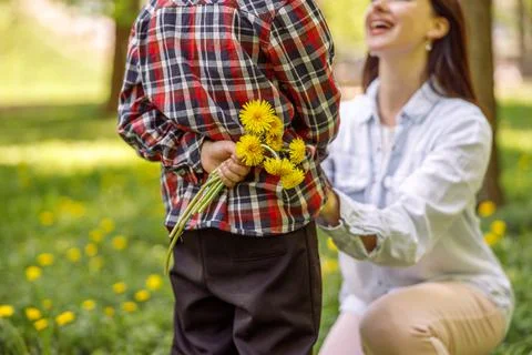 Close up of dandelions in small boy hand behind back before giving to mother Foto stock