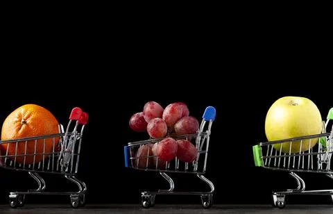 Close up, dark background image with three toy shopping carts filled with app Stock Photos