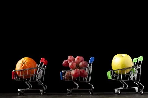 Close up, dark background image with three toy shopping carts filled with app Stock Photos