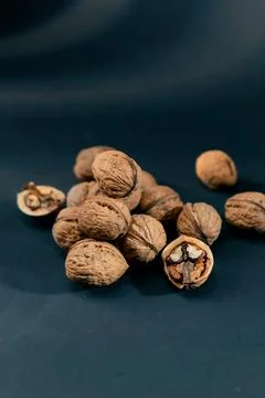 Close-up on dark blue background with side lighting lie whole and split walnuts Stock Photos