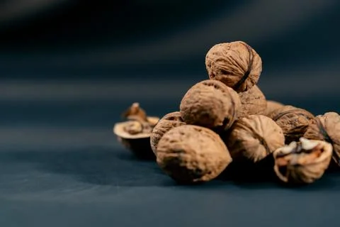 Close-up on dark blue background with side lighting lie whole and split walnuts Stock Photos