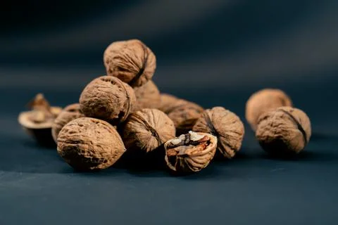 Close-up on dark blue background with side lighting lie whole and split walnuts Foto stock