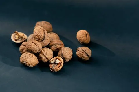 Close-up on dark blue background with side lighting lie whole and split walnuts Stock Photos