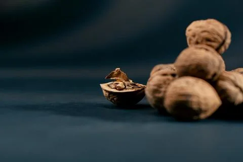 Close-up on dark blue background with side lighting lie whole and split walnuts Stock Photos
