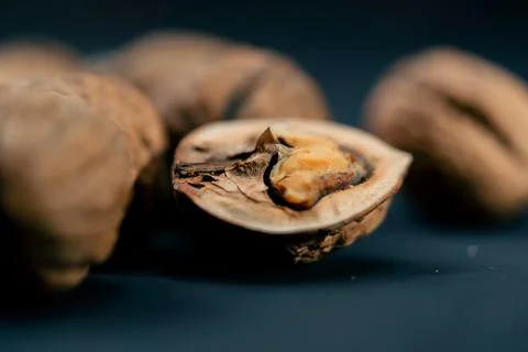 Close-up on dark blue background with side lighting lie whole and split walnuts Stock Photos