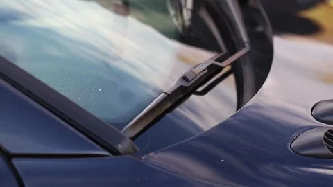 Close-up of a dark blue car windshield and wiper blades shaking from the Stock Footage 323908763
