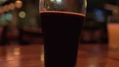 Close Up of a Dark Craft Beer Glass on a Pub Table Stock Footage 328337445