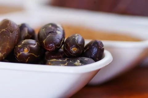 Close up of a dark dry cocoa bean inside of a white bowl 스톡 사진