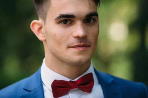 A close-up dark-haired guy with thick eyebrows, brown eyes and freckles gazes Stock Photos