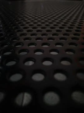 Close-up of a dark perforated metal surface Stock Photos
